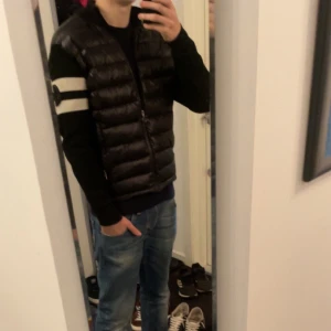  Moncler cardigan - Säljer en jävligt fet svart cardigan från Moncler. Den har en cool design. Ärmarna är långärmade med en vit randdetalj och Moncler-logga på ena ärmen. Perfekt för höst och vinter! Jag är 182 och den passar perfekt på mig. Priset är inte hugget i sten🙌