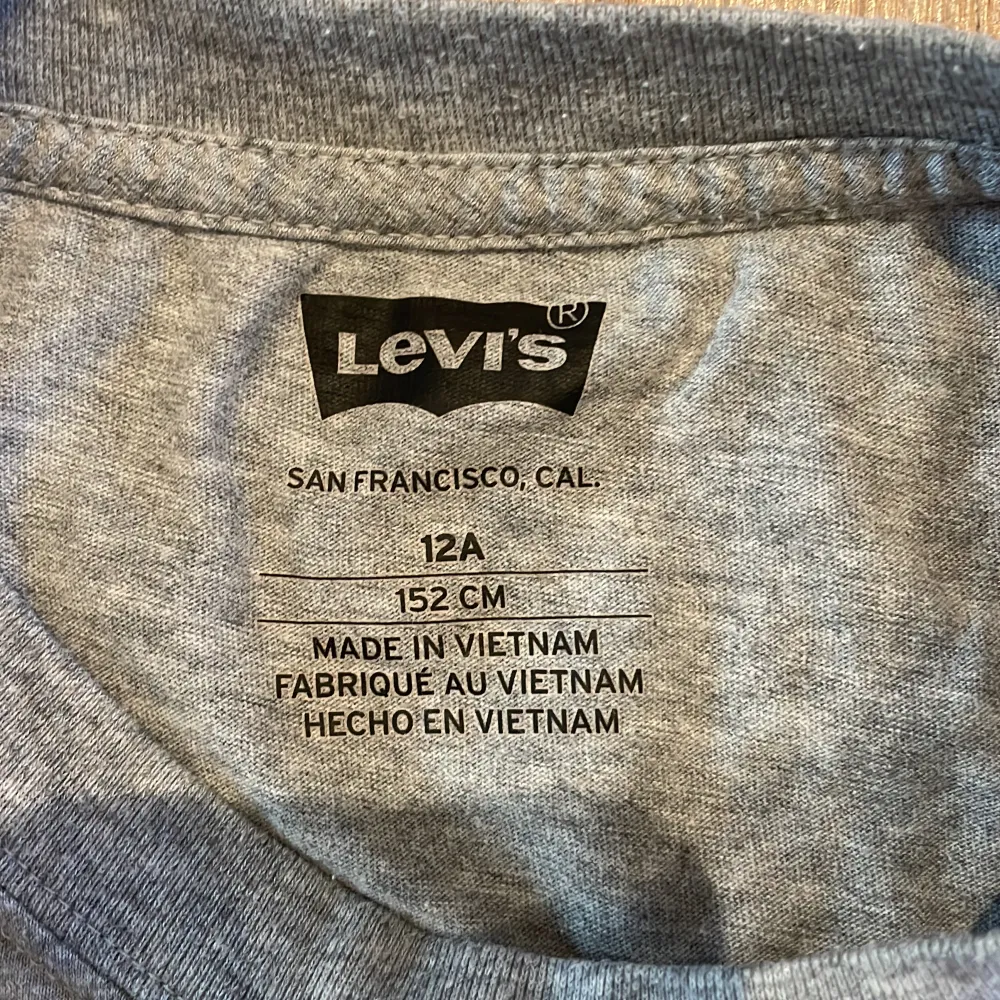 Säljer en snygg grå t-shirt från Levi's i storlek 12A (152 cm). Den har en klassisk röd och vit Levi's-logga på bröstet. Perfekt för vardagsbruk och passar till det mesta. T-shirten är i bra skick och gjord av mjuk bomull. Perfekt för både vår och sommar! Pris kan diskuteras!. T-paidat.