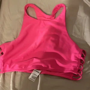 Rosa bikiniöverdel med snörning - Säljer en superfin rosa bikiniöverdel i mycket bra skick. Den har en sportig stil med hög hals och snygga snörningsdetaljer på sidorna. Perfekt för sommarens alla badäventyr! 💖