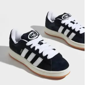 Säljer ett par snygga och klassiska Adidas Campus sneakers i svart mocka med vita detaljer. Helt nya och oanvända, storlek 39