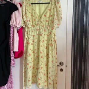 Gul blommig klänning - Fin gul blommig klänning, lite använd så fint skick  Snörning i midjan som kan framhäva midjan 