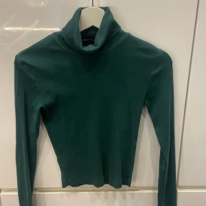 Mörkgrön polotröja - Säljer en stilren mörkgrön polotröja i ett mjukt och bekvämt material. Perfekt för kyliga dagar med sin långa ärmar och klassiska polokrage. Passar både till vardags och lite finare tillfällen. Ett måste i garderoben för höst och vinter!