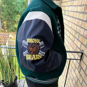 Grön collegejacka - Grön college jacka med mörkblå ärmar och gula detaljer o märken. Är storlek Medium men har en baggy fit