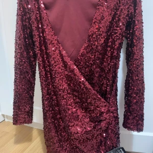 Glittrig vinröd festklänning - Klänningen är superfin och sitter perfekt på kroppen! Den är helt oanvänd.