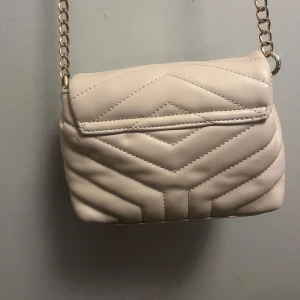 Handväska för billigt pris  - Den är använd för länge sen men inte sliten. En beige väska med guld kedja. Säljs då den inte används! 