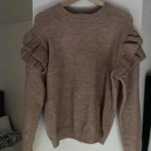 En fin ljusbrun tröja med volanger - Mysig till hösten och vintern och är i bra skick! Den är lite stor i storleken  