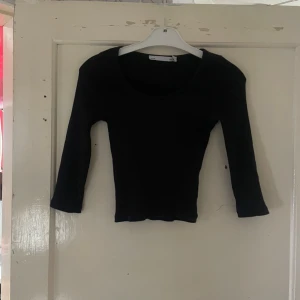 Svart långärmad topp i storlek XS/S - Säljer en stilren svart långärmad topp i storlek XS/S. Perfekt för både vardag och fest. Toppen har en enkel design med rund hals och är i ett mjukt och bekvämt material. Passar bra till jeans eller kjol för en avslappnad look.