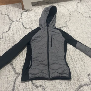 Grå och svart jacka med huva - Säljer en grå och svart peak performance jacka med huva. Den har en dragkedja framtill och är perfekt för en liten kall sommarkväll. Jackan är i bra skick.                Pris kan diskuteras 