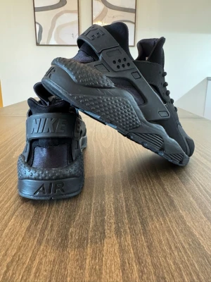 Nike Air Huarache i storlek 44.5 - Helt nya - Säljer ett par svarta Nike Air Huarache (artikelnummer: 318429-003), helt nya och oanvända i originalförpackning. De är väldigt bekväma och luftiga och har en klassisk helsvart färg som passar till det mesta. Säljs pga att de är något för små för mig. Kvitto finns och kan visas vid önskemål.  Storlek: 44,5