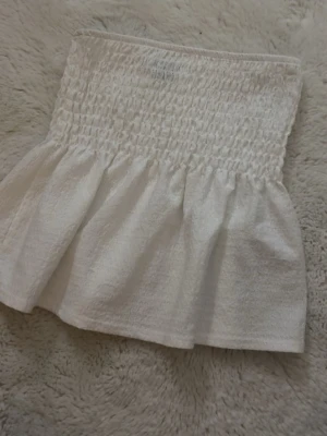 Vit bandeau topp från Gina Tricot - Supersöt vit bandeau topp från Gina Tricot med smockad överdel och volang nertill. Skriv om ni undrar nått mer!!💘💘