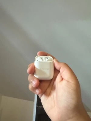 AirPods  - Säljer ett par vita trådlösa in-ear hörlurar med laddningsetui. Hörlurarna har en stilren och kompakt design, perfekt att ta med överallt. Etuiet är också vitt och har en smidig öppning för enkel förvaring och laddning.