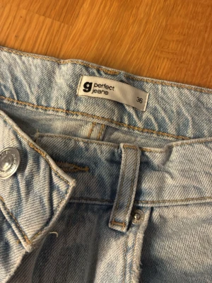 Ljusblå ripped jeans från g perfect - Säljer ett par ljusblå jeans från g perfect jeans i storlek 36. Jeansen har raka ben och slitna detaljer med stora hål vid knäna för en trendig och avslappnad look. Klassisk femficksmodell och tillverkade i denim.