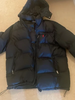 Svart polo Ralph lauren jacka - En snygg varm vinterjacka i väldigt skönt material. Dragkedjan till jackan har lossnat och finns ingen. Därav de billiga priset och tänker att ni kan köpa den billigare för att sedan kunna laga det hemma. 