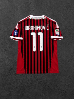 AC Milan Ibrahimović matchtröja - Säljer en röd och svart randig AC Milan matchtröja från Adidas med Ibrahimović och nummer 11 på ryggen. Tröjan har klubbmärke, sponsorlogga och vita detaljer på ärmar och krage. Perfekt för dig som älskar fotboll och vill stötta Milan.