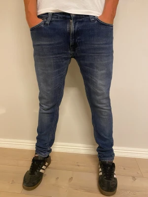 Mörkblå slim fit jeans herr - Snygga mörkblå slim fit jeans med klassisk femficksdesign och diskreta slitningar framtill. Jeansen har normal midja och smal passform hela vägen ner. Perfekta för en trendig och avslappnad look.