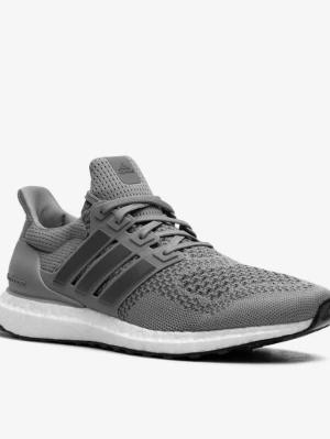 Grå Adidas Ultraboost sneakers - Snygga grå Adidas Ultraboost sneakers med stickad ovandel i mesh för skön andningsförmåga. Skon har de klassiska tre ränderna på sidan, Boost-mellansula för extra komfort och svart yttersula. Perfekt för dig som gillar stilrena och sportiga sneakers.