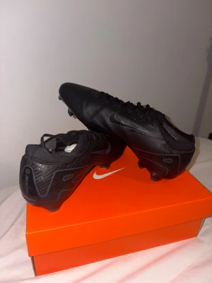 Nike Mercurial Vapor 16 Pro FG Svarta - Nike Mercurial Vapor 16 Pro FG fotbollsskor i helsvart med diskreta grå detaljer och Nike-logga. Snygg, strömlinjeformad design med snörning och platt sula med dobbar för gräsplan. Ovandel i syntetmaterial för lätt känsla och bra bollkontroll.