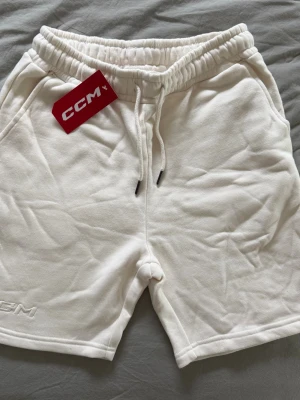 Vita mjukisshorts  från CCM - Vita shorts från CCM med elastisk midja och snörning framtill. Tillverkade i mjukt material. Diskret CCM-logga broderad vid benet och praktiska sidofickor. Lappar kvar, storlek S. Nypris ca 500kr.