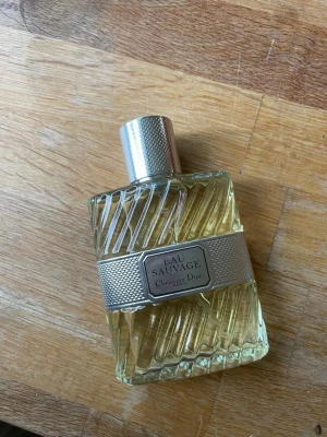 Eau Sauvage parfym från Dior - Eau Sauvage från Christian Dior är en klassisk parfym i en elegant glasflaska med snedräfflat mönster och silverfärgat metallband runt mitten. Flaskan har en silvrig metallkork och innehållet är ljust gult. Volymen är 100 ml Eau de Toilette. Endast testad en gång!