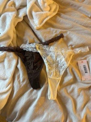 Stringtrosor från Nelly  - Säljer ett 2-pack stringtrosor i spets, en i svart och en i vitt. Båda har bred spetskant i midjan och transparent mesh med blommigt mönster. Perfekta för dig som gillar feminina detaljer och skön passform. Aldrig använda eller testade, säljer pga köpte fel storlek 