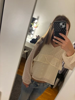 Ljusgul prickig blus med volang💛 - Söt Ljus gul blus med diskreta prickar och volangdetalj över bröstet. Blusen har v-ringning och är gjord i ett tunt, transparent material som ger en luftig känsla. Långa ärmar med resår vid handlederna för en avslappnad look.💞💞Original pris: 199