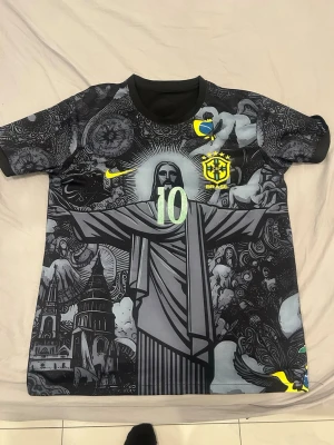 Brasilien Neymar Jr tröja svart/grå - Svart koncepttröja för Brasilien med Kristusstatyn och Neymar Jr 10 på ryggen. Begagnat skick, se bilder för trycket. 