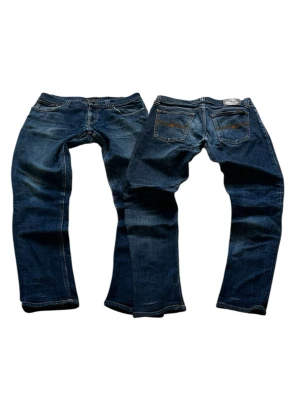 Blåa Nudie Tight Long John Jeans Storlek W30 L32 - Mycket fina Nudie Jeans i blå färg. | Jeansen är i mycket bra skick och sparsamt använda. |  Äkta som allt annat jag säljer! ✅ |  Storlek: W30 L32 | Skick: Mycket Bra Skick - tyvärr lagade på ett ställe vid skrevet och ett mycket litet hål. | Färg: Blå | Märke: Nudie | Modell: Jeans |   Hör gärna av dig vid frågor så svarar jag så fort jag kan! 😁 |  (SKU - 224)