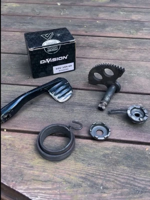 Kickstartdelar till moped DIVISION - Säljer ett kit med kickstartdelar till moped från DIVISION. Innehåller kickpedal, fjäder, kugghjul, låsringar och andra smådelar. Perfekt för dig som behöver byta eller laga kickstarten på din moppe.