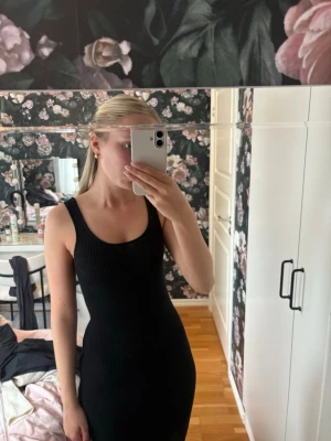 Svart ribbad långklänning - Säljer en svart ribbad långklänning med breda axelband och rundad ringning. Klänningen har en tight passform och är ärmlös, perfekt för en stilren och enkel look. Materialet är stretchigt och följsamt.🌸