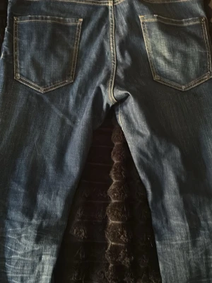 Blå jeans från Dsquared2, storlek 48 - Säljer ett par klassiska blå jeans från Dsquared2 i storlek 48. Jeansen har skinny ben, två bakfickor och snygga slitningar för en trendig look. Tillverkade i bomull med detaljerade sömmar och en autentisk tvättad finish. Bara 2 månader gamla o använda  runt 6 gånger för ja har många par