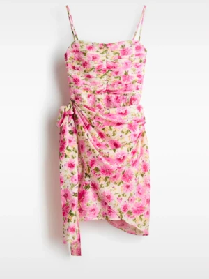 Blommig rosa kortklänning med knyt - Superfin kort klänning med blommigt mönster i rosa och grönt. Klänningen har smala axelband, draperad effekt och en snygg knytning i sidan. Perfekt för sommarens alla tillfällen och ger en fräsch och färgglad look.
