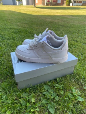 Nike Air Force 1 - Klassiska vita Nike Air Force 1 sneakers i lågt utförande. Skorna har en stilren design med perforerad tå, vit sula och Nike-logga på sidan. Storlek 41. Dom är använda men det syns endast på hälkragen, annars märks det inte. Skokartongen följer med!