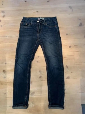 Levi's 512 Slim Taper jeans mörkblå - Säljer ett par Levi's 512 Slim Taper jeans i mörkblå denim. Klassisk femficksmodell med smal passform och avsmalnande ben. Snygga kopparfärgade nitar och detaljer. Perfekta för dig som gillar en clean och tidlös look.          