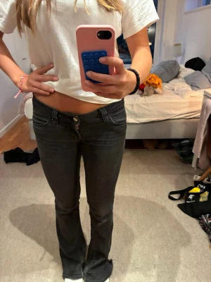 Svarta bootcut jeans - Säljer ett par svarta bootcut jeans med låg midja. Jeansen har klassisk femficksdesign och stängs med knapp och dragkedja. Snygg passform som sitter tight upptill och släpper ut vid bensluten. Perfekta för en trendig och avslappnad look. De är från weekday/cheap Monday 