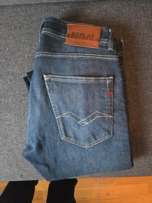 Mörkblå jeans från Replay - Snygga mörkblå jeans från Replay med klassisk femficksmodell och kontrastsömmar. Jeansen har en skinnpatch med Replay-logga bak i midjan och diskreta slitningar framtill. Perfekta för dig som gillar stilrena och tidlösa jeans.