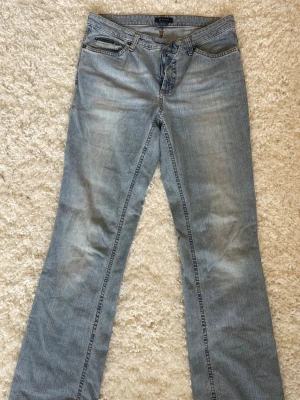 Ljusblå bootcut jeans från Gant - Säljer ett par mid waist ljusblå jeans från Gant med raka ben passform och klassiska fem fickor. Jeansen har snygga slitningar och kontrastsömmar. Perfekta för en avslappnad och trendig look.