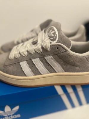 Gråa Adidas sneakers i mocka - Säljer ett par adidas campus i storlek 37 1/3, använda ett få tal gånger!!får att diskutera pris och även skicka fler bilder. Kommer även med extra snören och originala lådan. 