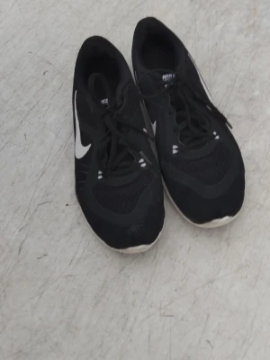 Svarta Nike sneakers med vit sula - Snygga svarta Nike sneakers med vit sula och vit swoosh-logga på sidan. Ovandelen är i mesh och syntetmaterial för bra andningsförmåga. Klassisk låg modell med snörning, perfekt för en sportig och avslappnad stil. Pris kan diskuteras 