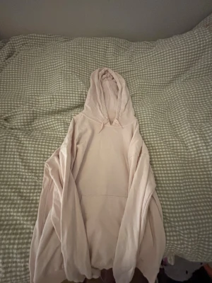 Ljusrosa oversized hoodie - En ljusrosa oversized hoodie med huva och känguruficka framtill. Hoodien har långa ärmar och ribbade muddar vid ärmslut och nederkant. Perfekt för en chill och avslappnad stil.