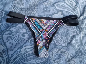 Färgglad bikiniunderdel med mönster - Säljer en bikiniunderdel med färgstarkt, geometriskt mönster i svart, vitt, blått, rosa och gult. Modellen har dubbla svarta band i midjan för en cool look. Perfekt för sommaren och strandhäng!