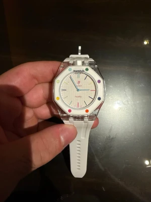 Swatch x AP Royal Oak klockor - Två Swatch x Audemars Piguet Royal Oak klockor. En med vit silikonrem och färgglada index, och en med svart silikonrem och svart urtavla. Båda har genomskinliga boetter och oktagonformad ram. Snygga och moderna accessoarer för dig som gillar statement-klockor. OBS, 3200kr  pris på en klocka, två för 6400 kr
