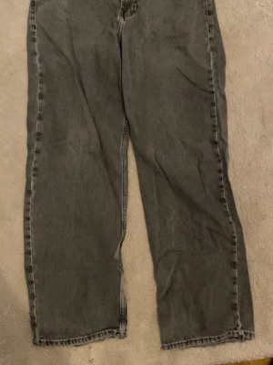 Gråa raka jeans Sweet Glitter - Säljer ett par gråa jeans med rak passform från Sweet sktbs . Jeansen har broderad logga vid fickan och råa kanter vid bensluten för en avslappnad look. Tillverkade i denim med en tvättad finish som ger en cool vintagekänsla.