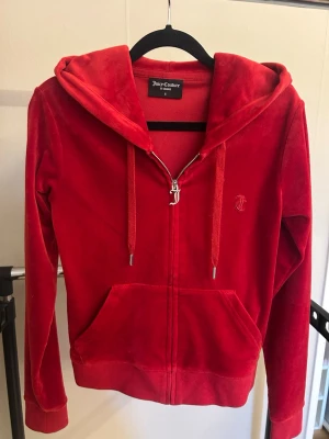 Röd velourhoodie Juicy Couture - Säljer en röd velourhoodie från Juicy Couture med dragkedja, huva och fickor framtill. Nästan aldrig använd.