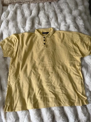 Gul pikétröja från Patagonia - Snygg gul pikétröja från Patagonia med klassisk krage och knappar framtill. Tillverkad i bomull och har korta ärmar. Diskret broderad logga på bröstet för en clean look.