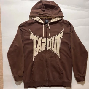 Tapout Hoodie - Brun Tapout hoodie med broderi. Höstfärger / earthy färger.  Väldigt fint skick skulle jag säga, se bilder för att själv avgöra.  Skicka ett meddelande om du har frågor eller vill se fler bilder 