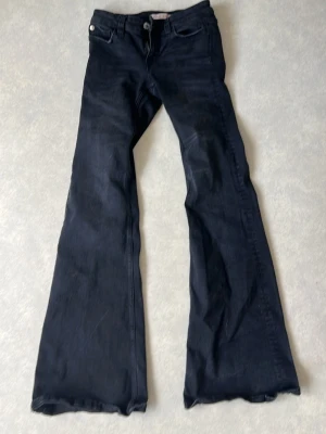 Svarta utsvängda jeans bootcut - Snygga svarta jeans med bootcut och utsvängda ben. Klassisk femficksmodell med knapp och dragkedja fram. Jeansen har en tidlös look och passar perfekt till sneakers eller boots. Materialet är denim med lätt stretch för skön passform.