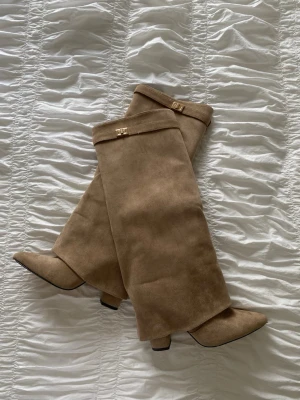 Beige knähöga boots från Raglady - Säljer ett par beige knähöga stövlar köpta från Raglady. Stövlarna har dekorativa guldfärgade spännen upptill och dragkedja på insidan. Perfekta för att lyfta vilken outfit som helst🤎