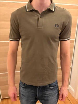 Fred Perry Piké - Mörkgrön Fred Perry Piké i storlek S. Den är i utmärkt skick utan några defekter eller tecken på användning. Tveka inte på att höra av dig vid frågor eller funderingar.