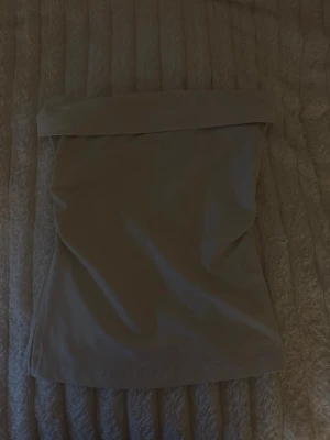Beige tubtop med slits - Snygg beige tubtop med bred kant upptill och draperad detalj på sidan. Toppen är figurnära och har en slits på ena sidan. Tillverkad i ett stretchigt och mjukt material som sitter bekvämt. 🤍