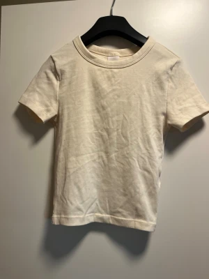 Ljus gul basic t-shirt från Gina Tricot - En enkel och stilren gul  t-shirt från Gina Tricot, kollektionen Elevated Basics. T-shirten har rund halsringning och korta ärmar. Tillverkad i mjuk bomull som känns skön mot huden. Perfekt att matcha med jeans eller kjol för en clean look.